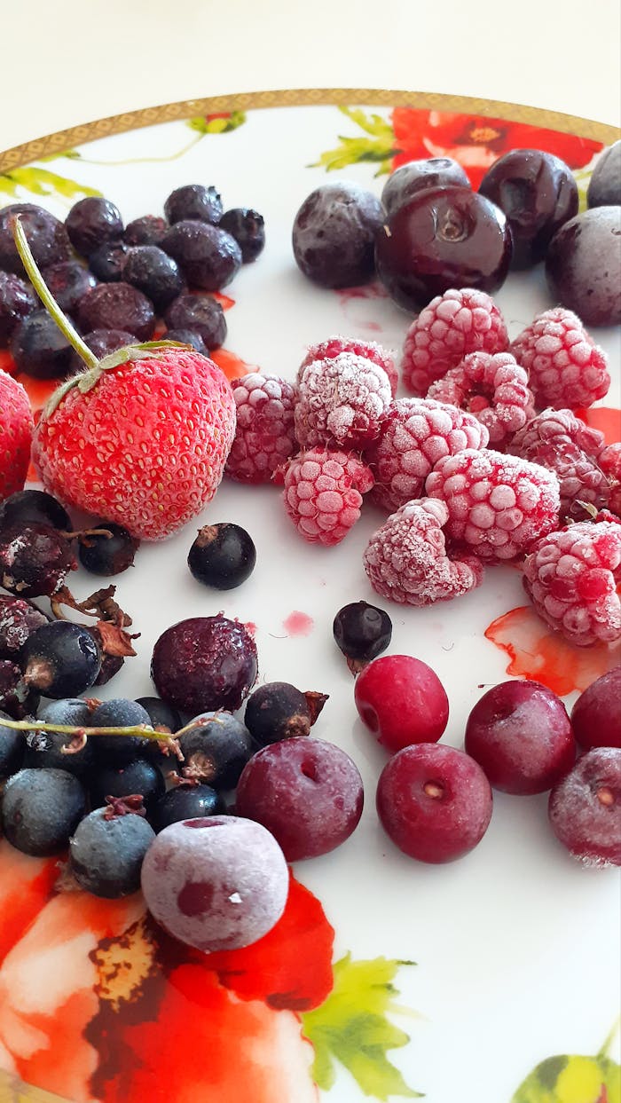 Vibrant array of fresh berries on a decorative floral plate, showcasing natural colors.